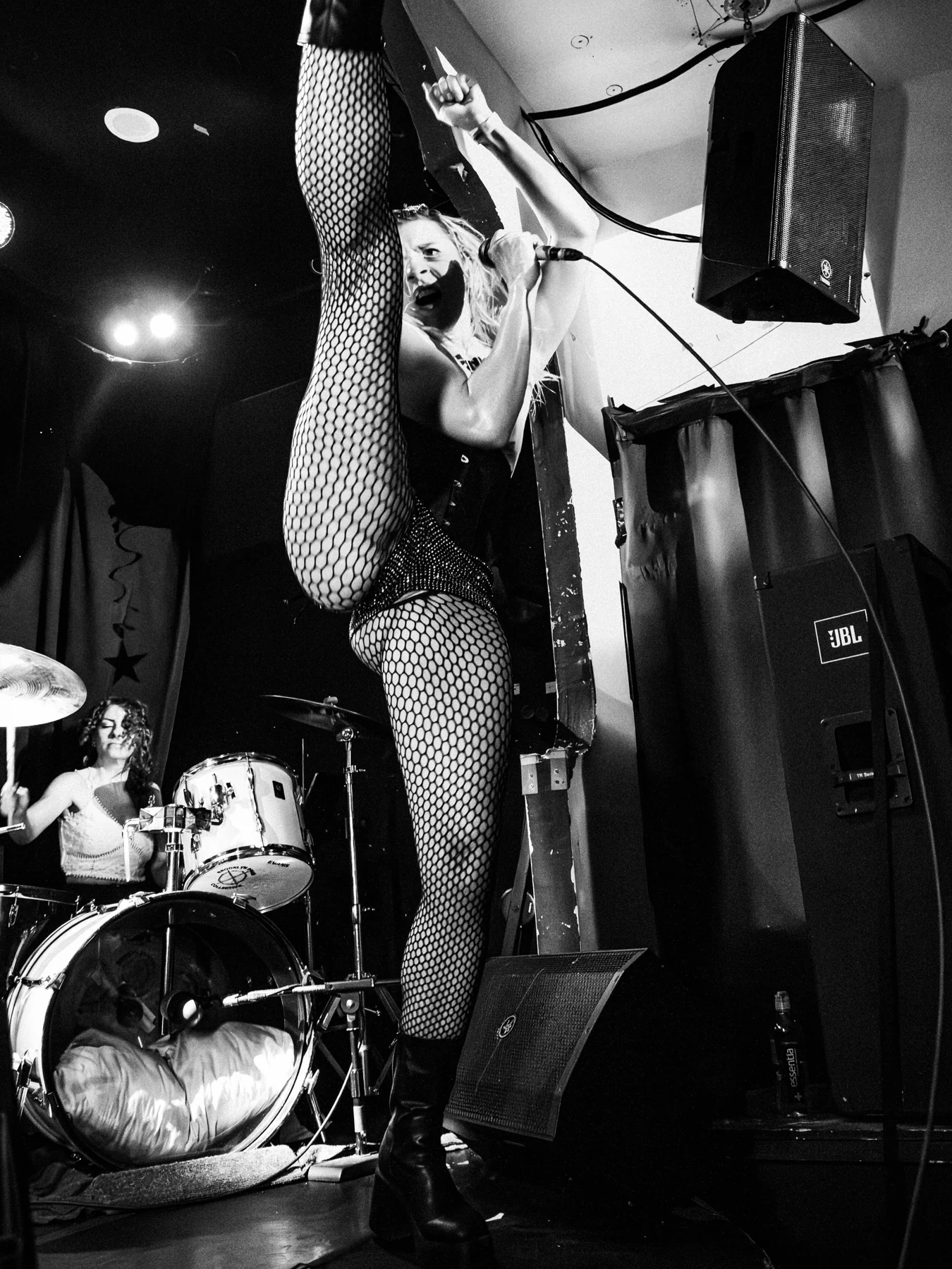 Sunday executing a high kick on stage in a black and white concert photograph